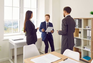 Bir grup genç iş adamı iş yerinde duruyor ve iş projesini toplantıda tartışıyorlar. İş arkadaşları ve şirket çalışanları iş arkadaşlarını dinliyor ve ara verdiklerinde ofiste konuşuyorlar..