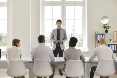 Erkek öğretmen kanepesi ders sırasında bir grup yetişkin öğrenciyle iletişim kurmayı öğretiyor. Öğrenci meslektaşları kameraların karşısında oturuyor. Kurumsal eğitim, seminer, eğitim, birlikte eğitim..