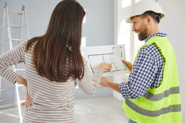 Foreman tasarım projesindeki genç ev sahibine planları gösteriyor ya da boş odada duran yeni dairesini onarıyor. İç dekorasyon hakkında müteahhitle görüşeceğim. Taşınma konsepti.