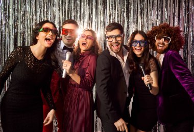 Mutlu arkadaşlar gece kulübünde parti sırasında mikrofonlu karaoke söyleyip dans ediyorlar. Müzik ve kutlamaların tadını çıkarıyorlar. Atmosferdeki eğlence ve eğlenceye odaklanıyorlar..