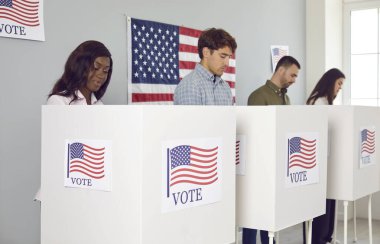 Bir grup mutlu Amerikan vatandaşının portresi. Seçim günü oy verme kabininde oy veren kadın ve erkekler oy kullanma merkezinde duruyor..