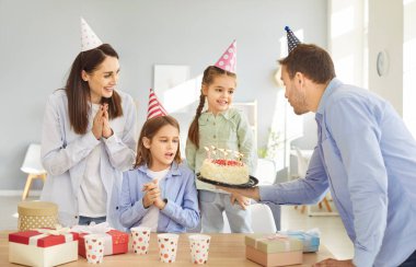 Mutlu yıllar mum pastası kutlaması, arkadaş canlısı aile, aileler ve çocuklar özel bir etkinlik için parti veriyor, gülümseyen insanlar toplanıyor, eğleniyor, eğleniyor, mutluluk diliyor, neşe diliyor, şapka takıyor.