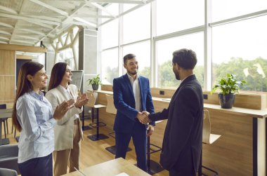 Şirket çalışanları başarıyı kutlamak için el sıkışıyor, anlaşma yapıyor, iş başarısı sağlıyor ya da sözleşme imzalıyor. Bir grup iş adamı bir toplantıda iş arkadaşlarını alkışlıyor..