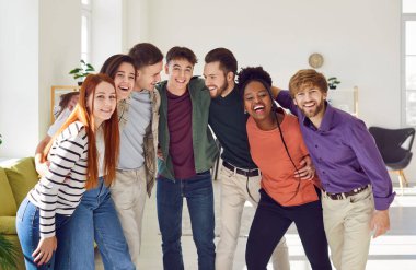 Mutlu gülümseyen komik arkadaşlar ya da sıradan kıyafetler giymiş meslektaşlar birlikte gülüyor, neşeli ve pozitif bakıyorlardı. Dost canlısı erkekler ve kızlar içeride sarılıyorlar..