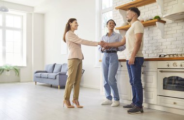 Çift, emlakçı modern kapalı alanda el sıkışma, profesyonel danışma, satmadan önce odaklanmış ve meşgul tartışma, yeni aile sahipleri için ev, arazi ve bina kiralama