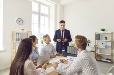 Erkek işveren, ofis çalışanlarıyla takım iletişimi ve bağlantısına odaklanarak bir toplantı düzenler. Meslektaşlar ortak iş amaçlarına ulaşmak için işbirliği yaparlar.
