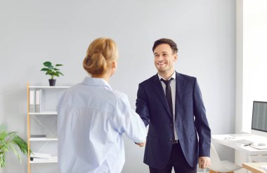 İki mutlu, gülümseyen iş adamı ve kadın ofiste el sıkışıyor, anlaşmaya varıyor, iyi anlaşmalar yapıyor, yeni ortağını tebrik ediyor ya da yeni çalışanı selamlıyor. Başarılı ortaklık.