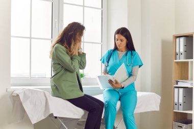 Hasta, doktor muayenehanesinde baş ağrısı ya da migren şikayetiyle oturan genç bir kadın. Klinikteki tıbbi muayene sırasında kadın hasta. Sağlık ve Tıp Konsepti.