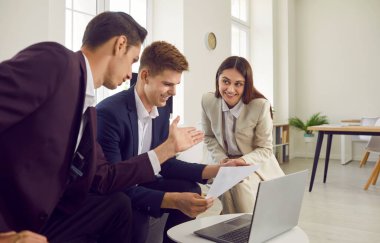 Üç şirket çalışanı konuşuyor ve tartışıyorlar, yeni projeler ve girişimler üzerinde düşünüyorlar, şirketleri analiz ediyorlar. Ofisteki laptopta çalışan kendinden emin genç iş adamları. Takım çalışması konsepti.