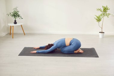 Yogi genç sporcu kadın yoga dersleri alıyor. Çocuk egzersizi, Balasana pozu, spor, kapalı alanda spor, spor salonu, spor salonu yeşil ev bitkileri arasında atölye eğitimi.
