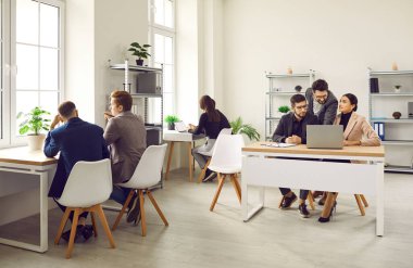 Ofiste çalışan iş adamları. Kurumsal işçiler ve iş adamları toplanıyor, projeleri tartışıyor ve aydınlık, ferah bir ofis içinde dizüstü bilgisayarlar üzerinde çalışıyorlar.