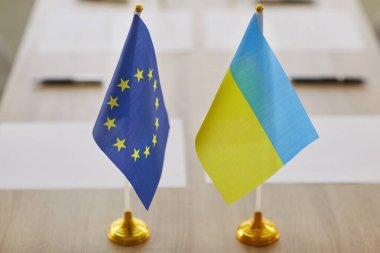 Avrupa Birliği ve Ukrayna bayrakları konferans masasında birlik ve işbirliğini simgeliyor. Ukrayna 'nın Avrupa Birliği' ne katılım adayı statüsü var. Ukrayna 'ya Giriş