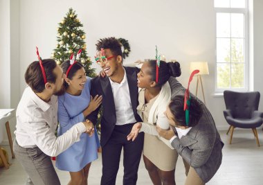 Bir grup mutlu yetişkin arkadaş evdeki Noel partisinde eğleniyor. Noel ağacıyla oturma odasında dikilmiş komik şakalara gülen çeşitli Noel bantlı neşeli genç insanları heyecanlandırdı.