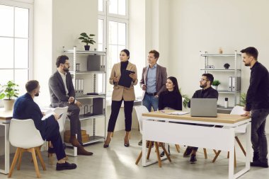 İş arkadaşları ofiste toplantı sırasında tartışıyorlar. Genç profesyonellerden oluşan bir ekip, iş meselelerini açıklayan, beyin fırtınası yapan ve fikirlerini paylaşan patron erkek takım liderlerini dinliyor.