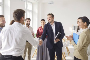 Neşeli ve olumlu iş arkadaşları ofiste yaptıkları bir iş toplantısında el sıkışırlar. Takım çalışması, ortaklık, işbirliği ve başarılı bir profesyonel anlaşmanın tamamlanması..