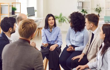 Çeşitli iş arkadaşları daireler çizerek oturuyor, grup terapisi toplantılarında konuşuyor, bağımlılığı tartışıyor, ofis sorunları, çok ırklı çalışanların takım çalışmasında beyin fırtınası yapıyor.