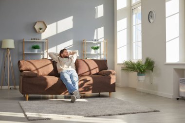 Modern evdeki oturma odasındaki rahat koltukta oturan ve pencereye bakan genç ve rahat bir adam. Sakin sakin adam dinleniyor ve rüya görüyor..