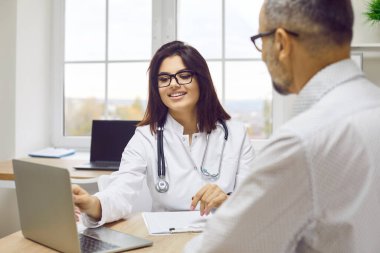 Doktor dizüstü bilgisayar kullanarak hastanın test sonuçlarını ve teşhisini tartışıyor. Klinikteki sağlık kontrolünde orta yaşlı bir adamla konuşan profesyonel bir pratisyen. Sağlık hizmetleri kavramı