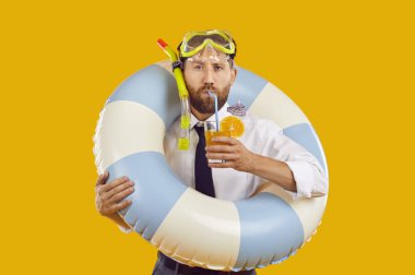 Dalgıç gözlüğü takmış, portakal suyu içen komik sakallı bir adamın portresi. Stüdyo sarı arka planda izole edilmiş şişirilebilir kauçuk yüzük tutuyor. Yaz tatili ve tatil konsepti