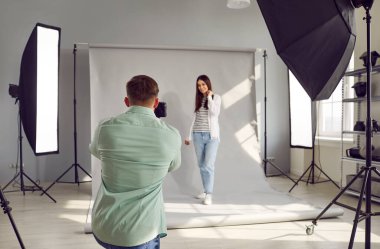 Modern stüdyoda profesyonel fotoğraf ekipmanlarıyla çalışan fotoğrafçı ve model. Erkek fotoğrafçının, dijital fotoğraf makinesiyle kadın modelin fotoğraflarını çektiği nadir görüntüler.