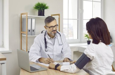 Gülümseyen erkek doktor kadın hastaya baskı yapıyor. Terapist sonuçları analiz ediyor ve klinikteki kadın reçetesini açıklıyor. Tıbbi tedavi ve sağlık hizmeti kavramı