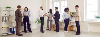 Ofis çok ırklı iş arkadaşlarıyla birlikte çalışma alanında gruplar halinde duran, çeşitliliği destekleyen, kurumsal başarıyı, takım çalışmasını, konuşmayı, görüşmeyi bekleyen başvuru sahiplerini 