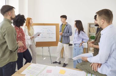 Team of young creative diverse people having a work meeting in the office, giving presentations, discussing business ideas and ways to achieve success together