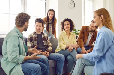 Bir grup mutlu genç arkadaş evdeki oturma odasındaki kanepede oturmuş birbirleriyle konuşup eğleniyorlar. Arkadaşlık, parti ve ev eğlencesi konsepti.