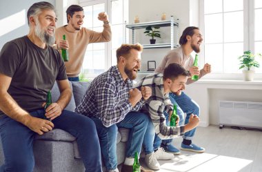 Portrait of excited happy male friends watching sport football match on tv with beer supporting their favourite team together at home. Friendship, leasure, sport,home party concept.