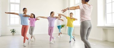 Gülümseyen mutlu kızlar, modern dans figürlerini kadın koreografla birlikte stüdyoda çalışırlar. Koreografi dersinde dans egzersizi yapan bir grup çocuk. Çocuklar spor ve aktif yaşam tarzı konsepti.