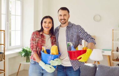 Young happy couple clean, man and woman janitor pair with house cleaning materials. Family new flat, professionals maintaining cleanly facility, home sanitation and room cleanliness, domestic life