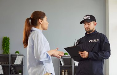 Witness interview by police officer recording notes on clipboard, cop listening woman and writing crime facts in official report. People standing in living room, witness explaining details