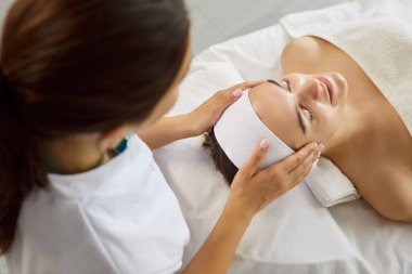 Facial massage therapy for client, spa treatment for relax and skincare in cosmetologists office. Hands of professional beautician massage face skin of woman on relaxing session. Cosmetology concept