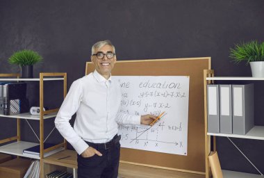 Modern education. Math teacher teaches remotely. Portrait of a friendly senior male lecturer who online explains mathematical formulas to students. Online education concept.