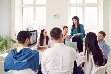 Professional team in an office holding a group work meeting or training session. The business setting emphasizes communication, teamwork, and the collective effort of the people involved.