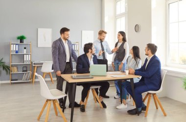 Bir konferans sırasında modern ofiste oturup yeni iş projelerini ya da girişimleri tartışan kendine güvenen genç şirket çalışanları grubu. Takım çalışması konsepti.