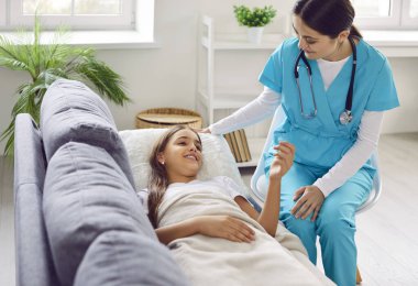 Doctor visits a sick child patient at home. Friendly woman pediatrician in scrubs visits a little girl to check on her during her illness. Health care, sickness, medical checkup concept