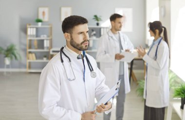 Serious and focused male medic coworker thinking, clinic team collaboration, leader with colleagues appreciate for help praise good work acknowledge competence, share ideas, attentive talk in room