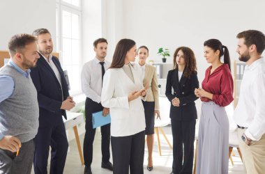 Office staff members meeting, people gathered in coworking area to solve business task, listen to female team leader during briefing, boss shares information planning corporate goals, telling