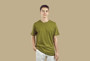 Confident smiling peaceful young boy student wearing casual clothes isolated on a studio beige background. Smart guy looking at camera indoors. People portrait and emotions concept.