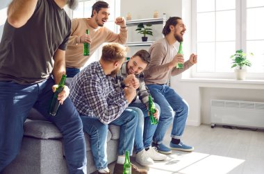 Portrait of excited happy male friends watching sport football match on tv with beer supporting their favourite team together at home. Friendship, leasure, sport,home party concept.