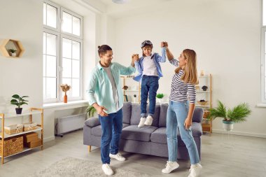 Mutlu gülümseyen aile, evdeki oturma odasında oğluyla eğleniyor. Bir çift havalanıyor. Pilot gözlüklü neşeli çocukları onunla uçak oyunu oynuyor..