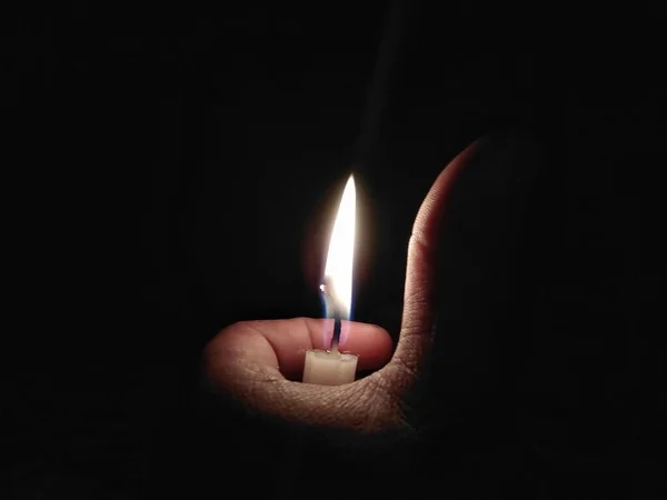 手拿着燃烧的蜡烛在黑色的背景上 — 图库照片