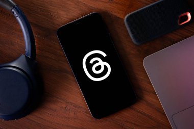 Instagram 'dan bir Flatlay of Threads masadaki diğer teknoloji ürünleriyle birlikte bir telefonda açıldı