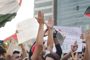 İnsanlar Filistin protestolarında poster asıyor. 