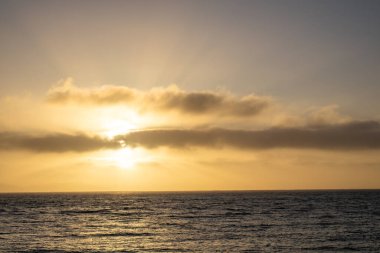 Okyanus kıyısında gün batımı. Güneş ışınlı bulutlar. Deniz manzarası. Okyanus manzarası. Bulutlu doğa arka planı. San Fransisco Körfezi bölgesi.