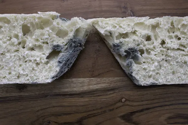 Ahşap kesme tahtasındaki küflü ekmek parçası. Küf içinde çürümüş bir somun ekmek mutfak tahtasının üzerinde çürüyor. Ahşap atık kavramı.. 