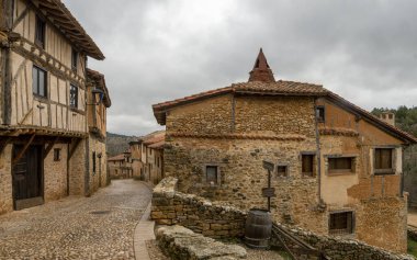 Calataazor 'un zamansız çekiciliğini bu büyüleyici sokak fotoğrafçılığıyla keşfedin, burada, karmaşık dokuma mimarisi gözler önüne seriliyor. Kaldırımlı sokakların kırsal güzelliğine dalın kendinizi.