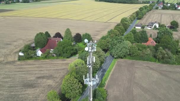個々の家を持つ田舎の風景のアンテナが付いている信号のデジタル伝達のためのタワー 回転ドローンショット — ストック動画