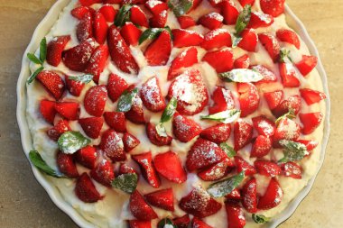 Krem şantili bir kekin içinde çilek dilimleri. Nane yapraklı vinç planıyla kesilmiş olgun çilek parçaları.